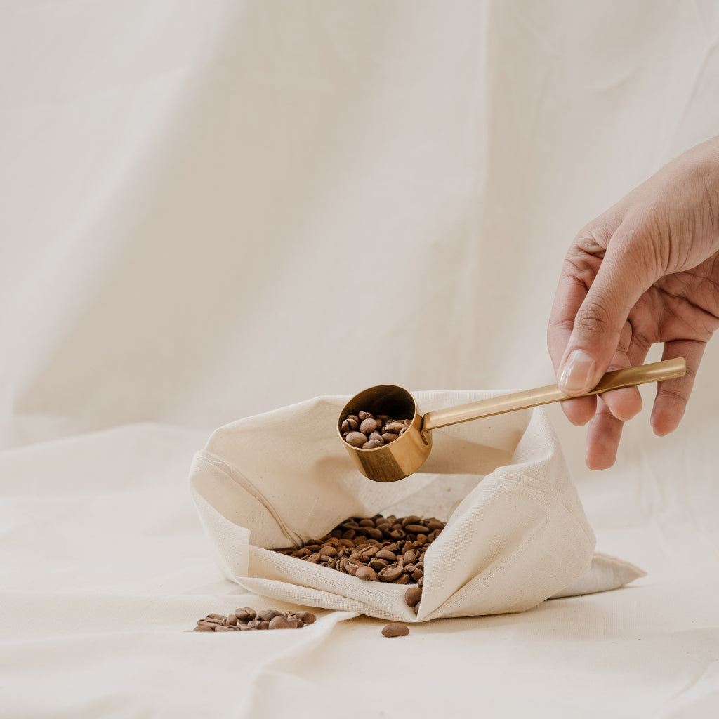 Coffee beans being scooped out of a cloth reusable bag