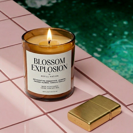 Candle labeled 'Blossom Explosion' by Refill Nation on a tiled surface near a pool.